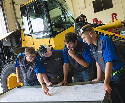 four male workers analyzing a blueprint
