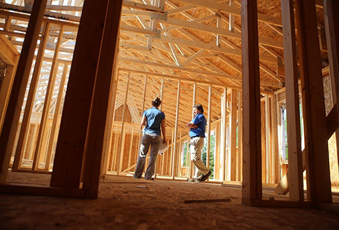 two construction workers discussing inside an ongoing wooden construction site